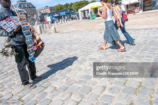 Vendeur à la sauvette de cartes postales et de tours Eiffel en porte-clés et touristes devant le chateau de Versailles, 31 août 2006, Versailles,...