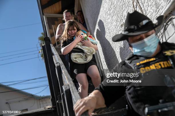 Maricopa County constable Darlene Martinez escorts a family out of their apartment after serving an eviction order for non-payment on September 30,...