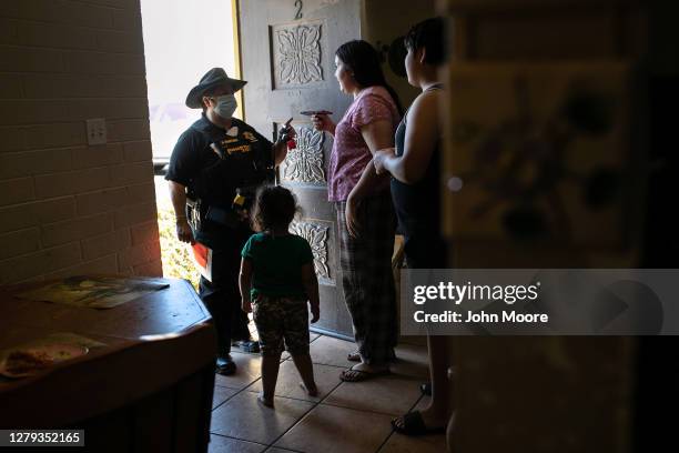 Maricopa County constable Darlene Martinez speaks to a renter by phone about an eviction order as the tenant's children translate on October 1, 2020...