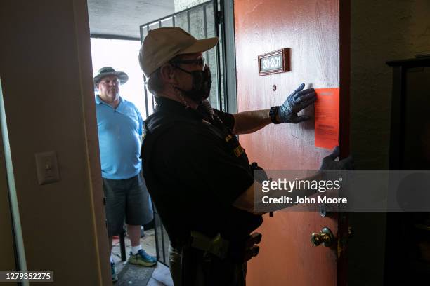 Maricopa County constable Lenny McCloskey posts an eviction order on the door of an apartment September 30, 2020 in Glendale, Arizona. Thousands of...