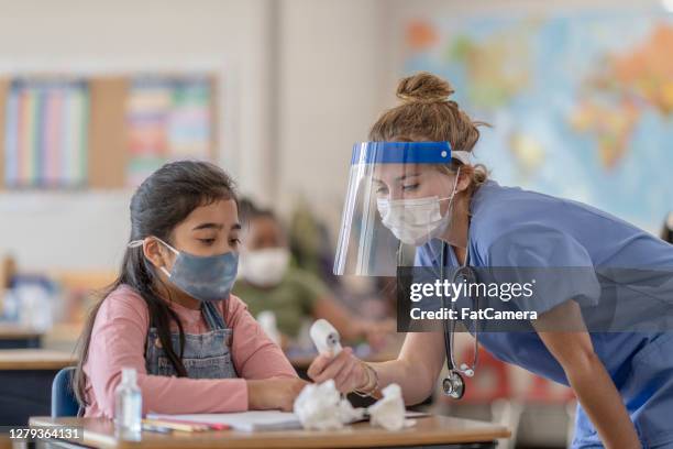 school nurse checking child for covid-19 symptoms - taking temperature stock pictures, royalty-free photos & images