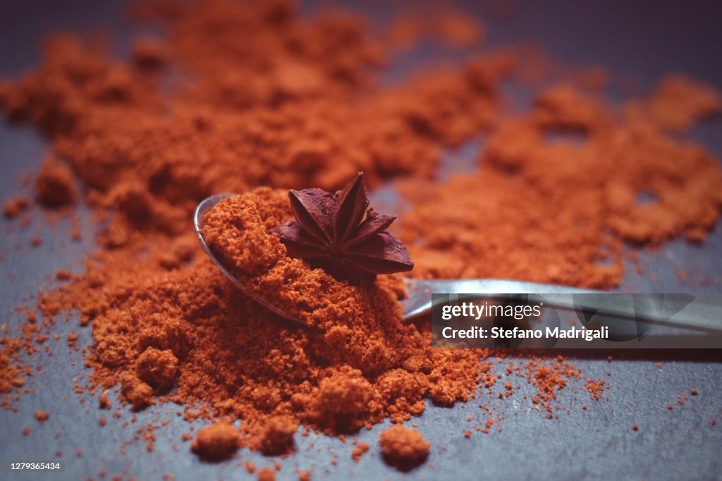 Spoon with spices powder and anise seed, black slate background