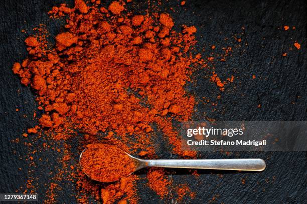 spoon with spices colored powder, black slate background - チリパウダー ストックフォトと画像