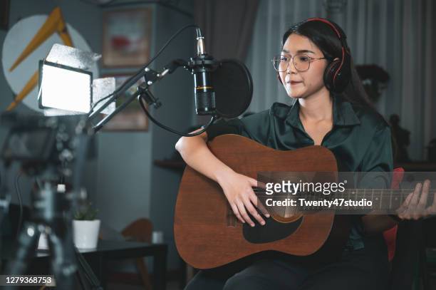 female influencer playing acoustic guitar recording live stream - acoustic guitar stock-fotos und bilder