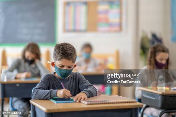 studenti che indossano maschere in classe - educazione foto e immagini stock