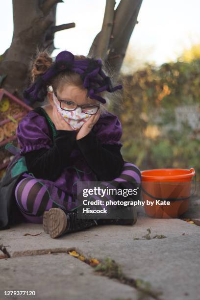 sad girl in protective face mask next to a  trick or treat bucket - 2020 glasses stock pictures, royalty-free photos & images