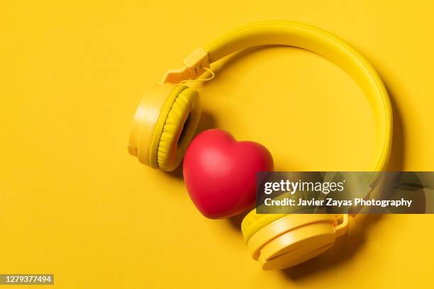 yellow headphones on yellow background and a heart - mp3 gerät stock-fotos und bilder