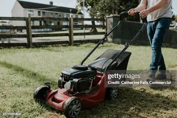 man pushing a lawn mower in a garden - lawnmower engine stock pictures, royalty-free photos & images