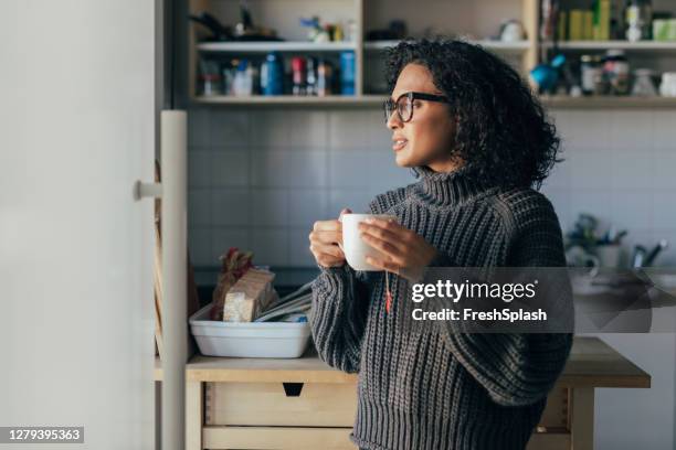 gezonde ochtend gewoonten: een jonge vrouw drinken hot tea in de keuken - cozy kitchen stockfoto's en -beelden