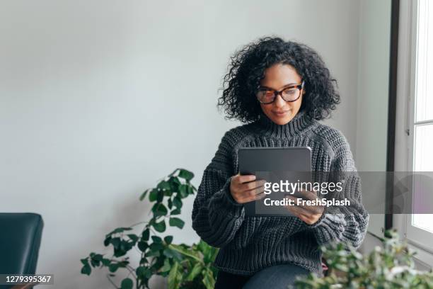 在家工作:一個年輕女子使用數位平板電腦閱讀/觀看的東西。 - reading 個照片及圖片檔