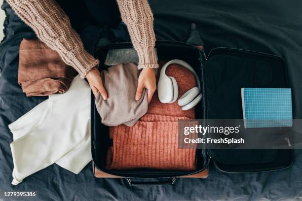 hands of an anonymous woman packing her suitcase for winter holiday, an overhead view - pack imagens e fotografias de stock