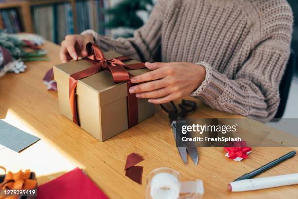 クリスマスの準備:彼女の愛する人のためのクリスマスプレゼントを梱包匿名の女性の手 - 包装紙 ストックフォトと画像