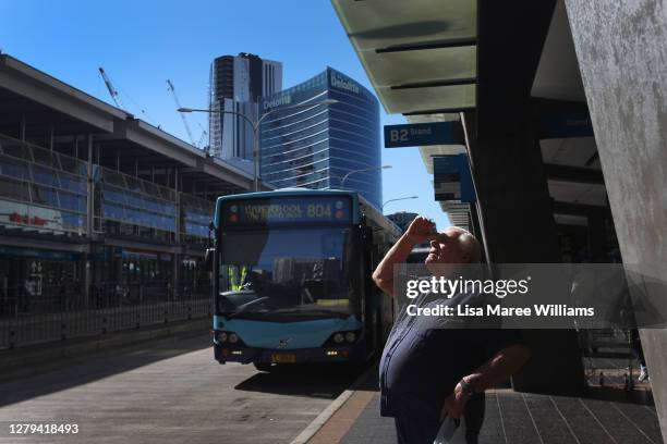 Man looks up towards the sky as he waits to board a bus at the Parramatta transit hub on October 10, 2020 in Sydney, Australia. Sydney residents are...