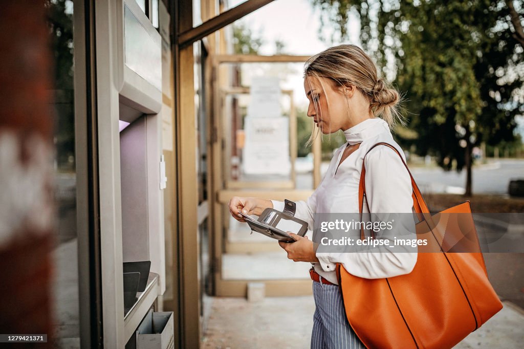 Kvinnor som använder bankomat för att ta ut pengar