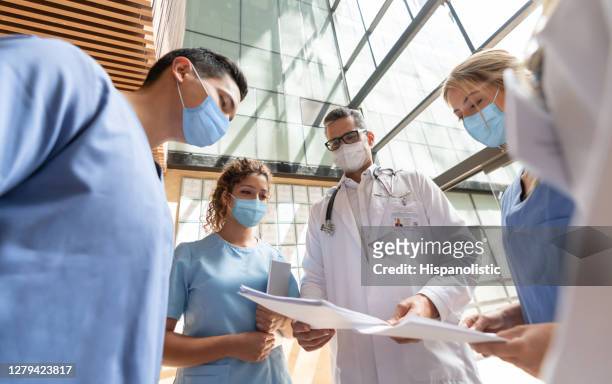 group of doctors talking at the hospital and wearing facemasks - n95 face mask medical stock pictures, royalty-free photos & images