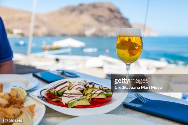 glass of beer and plate of salad and fish, with the sea in the background - almeria restaurant stock-fotos und bilder