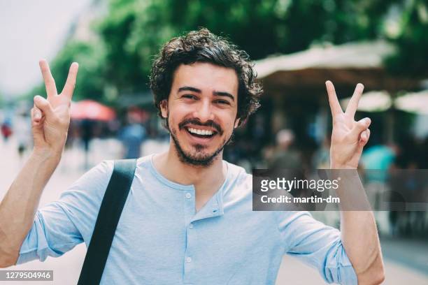 gelukkige mens die een v-teken met beide handen geeft - victory sign man stockfoto's en -beelden