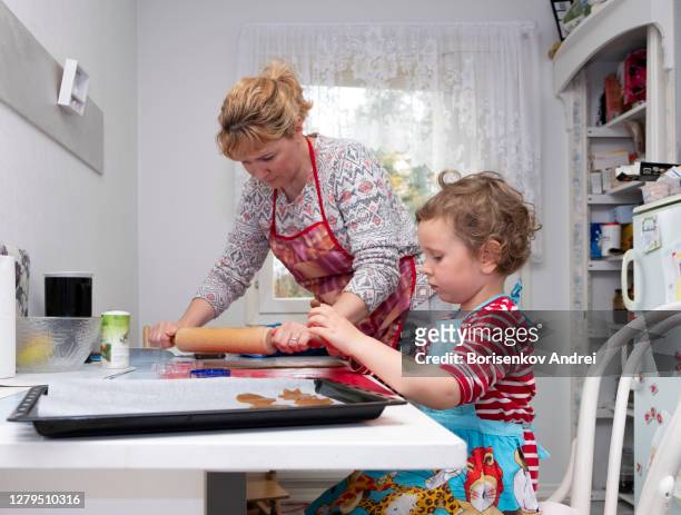 a girl and a woman, caucasians, bake gingerbread cookies in the kitchen. family concerns. - ginger snap stock pictures, royalty-free photos & images