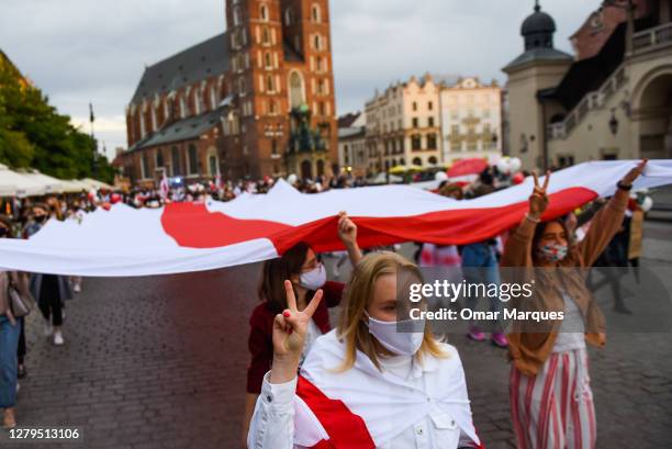 Demonstrators wearing protective face masks chant and hold a giant Belarus flag the "You go girl! Women's march for Belarus" on October 10, 2020 in...