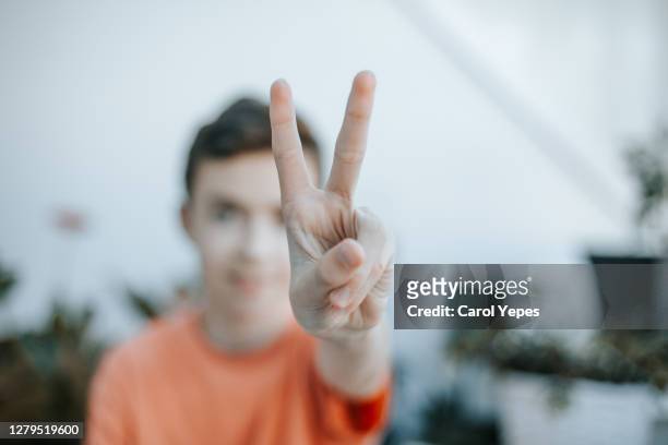 portrait of smilng teenager showing victory-sign - hand gestures stock pictures, royalty-free photos & images