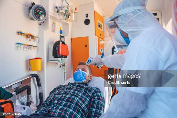 paramedic with protective hazmat suit measuring temperature of a patient in ambulance during pandemic - thermometer turkey stock pictures, royalty-free photos & images