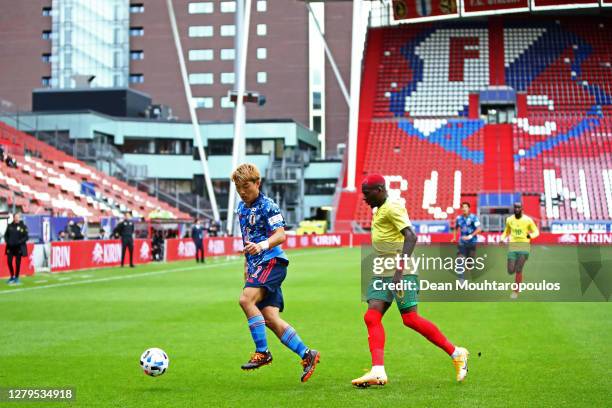 Ritsu Doan of Japan battles for the ball with Ambroise Oyongo of Cameroon during the international friendly match between Japan and Cameroon at...