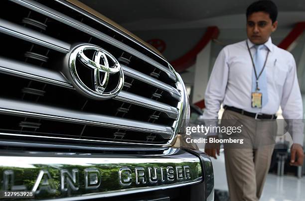 An employee walks past a Toyota Motor Corp. Land Cruiser sport-utility vehicle at the Toyota Central Motors dealership in Karachi, Pakistan, on...