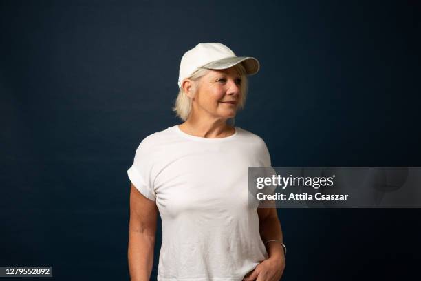 mature sporty woman looking at distance wearing baseball cap - woman white t shirt stock pictures, royalty-free photos & images