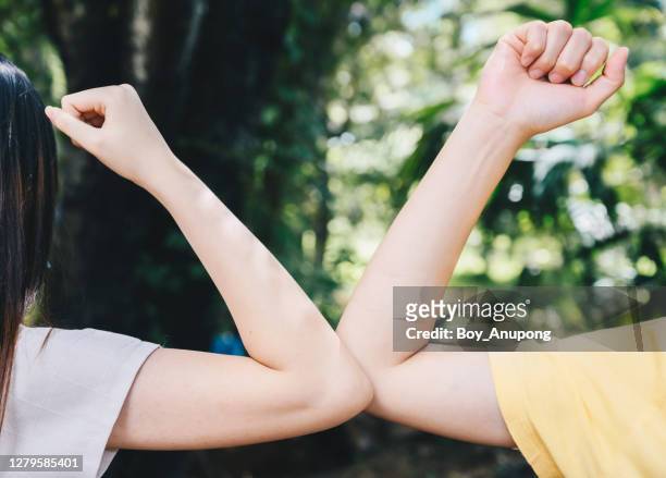 cropped shot of two women bump elbows for greeting during coronavirus epidemic. - ellenbogen stock-fotos und bilder