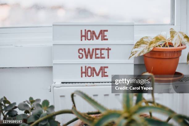 home sweet home text in lighbox with house plant around - home sweet home stockfoto's en -beelden