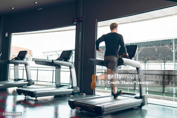back view of a man running on a treadmill - running on treadmill stockfoto's en -beelden