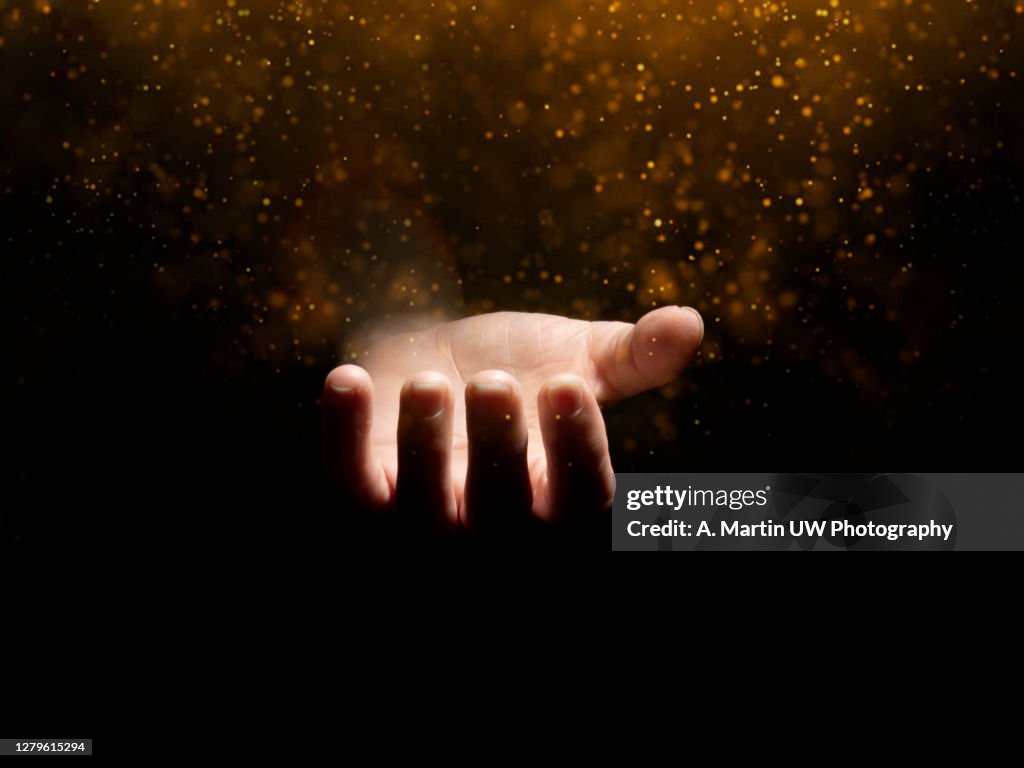 Praying hands with faith in religion and belief in God on blessing background. Power of hope or love and devotion. Magic powder floating on the magician hand.