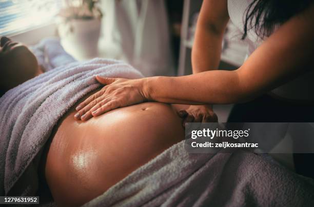 mujer embarazada teniendo masaje en spa relajarse - massaging fotografías e imágenes de stock