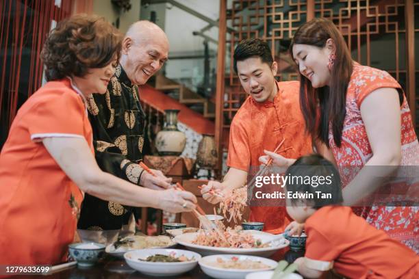 asiatique chinois famille chinoise dîner de réunion nouvel an ayant des plats traditionnels de poisson cru lau chanté yee chanté - chinese new year food photos et images de collection