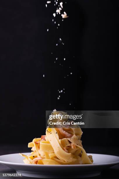 tagliatelle carbonara dish with parmesan cheese falling from above - falling food stock pictures, royalty-free photos & images