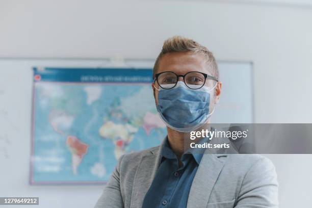 portrait of young male teacher with face mask in classroom - teacher mask stock pictures, royalty-free photos & images