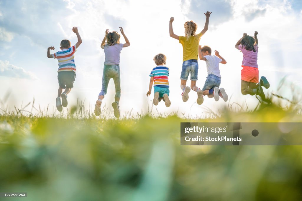 Rear view group of kids jumping in nature