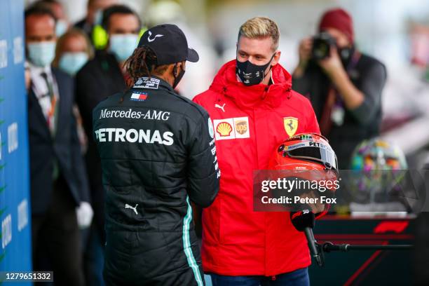 Mick Schumacher of Germany and Ferrari presents Lewis Hamilton of Mercedes and Great Britain with his father Michael Schumacher's helmet to celebrate...