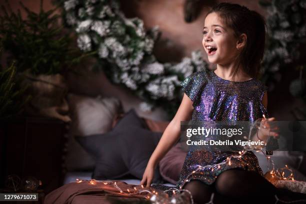 aufgeregtmädchen in hübschen kleid spielen mit weihnachtsbeleuchtung - mädchen kleid stock-fotos und bilder
