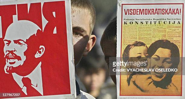 Boys hold Communist propaganda posters during a rally marking the 90th anniversary of the October Revolution near a monumet to Vladimir Lenin, the...