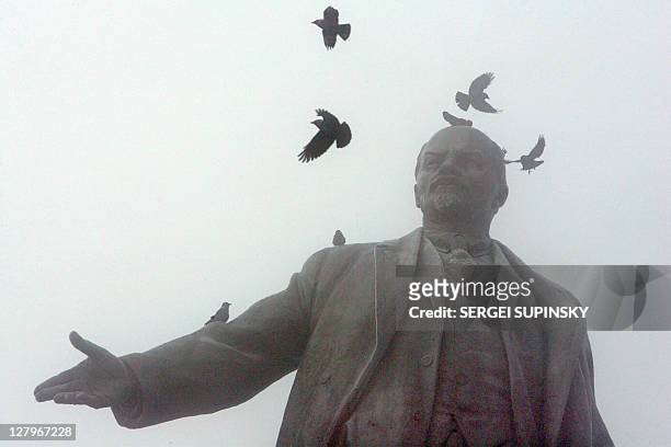 Crows fly over Lenin's monument in the center of Ukrainian city of Kharkiv during heavy fog on February 4, 2008. AFP PHOTO/ SERGEI SUPINSKY