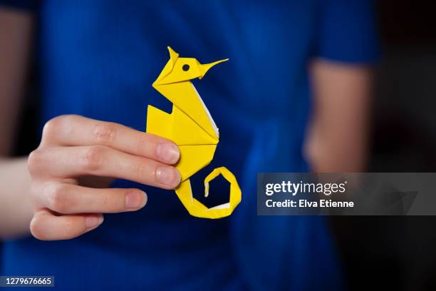 teenager holding homemade origami sculpture of a seahorse made from yellow paper - yellow seahorse stock pictures, royalty-free photos & images