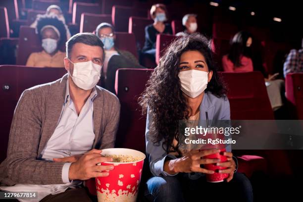feliz pareja usando máscaras faciales en el cine - lovers 2020 film fotografías e imágenes de stock