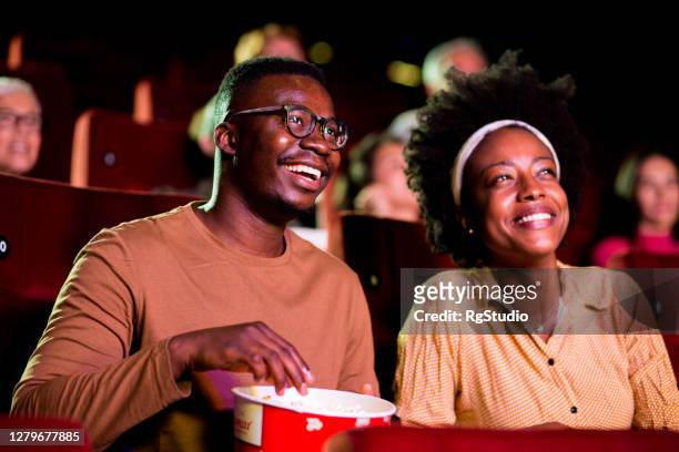 african-american couple enjoying while watching a fun movie at the cinema - black theatre stock pictures, royalty-free photos & images
