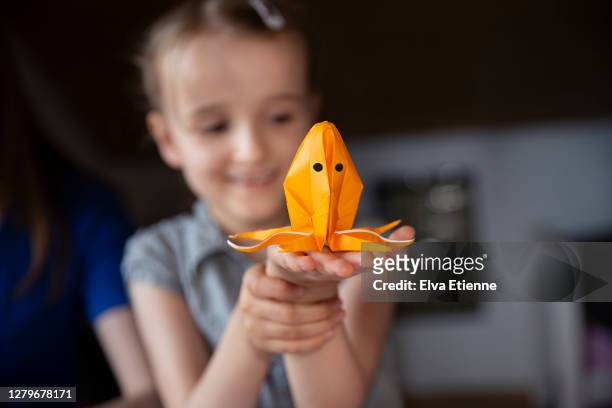 child holding homemade origami sculpture of an octopus made from orange paper - invertebrate stock pictures, royalty-free photos & images