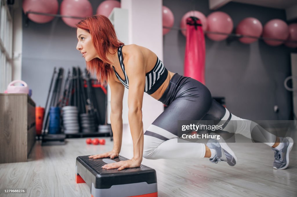 Joven atleta atleta trabajando en plataforma paso a paso en el gimnasio