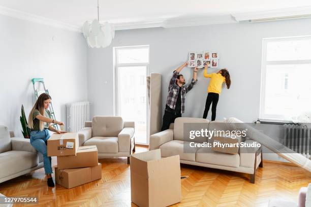 mentre il padre pubblica una foto con la figlia nella loro casa appena trasferita, la madre apre le scatole rimanenti - appendere quadro foto e immagini stock