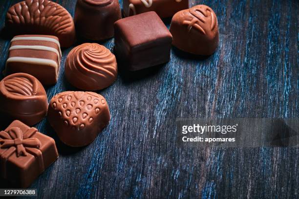 low-key-bild einer vielzahl von schokolade und bombonen auf einem blauen rustikalen tisch mit kopierraum - bombones chocolate stock-fotos und bilder