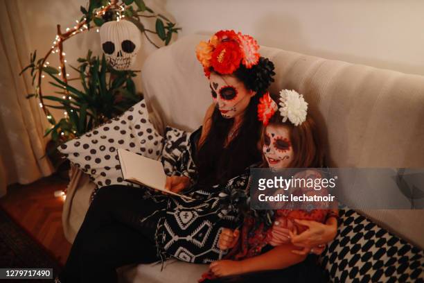 mom reading spooky tales to her daugher on the day of the dead - dead girl imagens e fotografias de stock