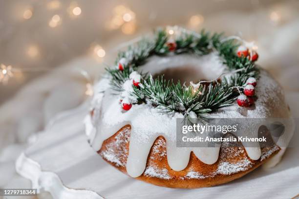 traditional christmas lemon bundt cake decorated with spruce branch and cranberrys. - christmas cake foto e immagini stock